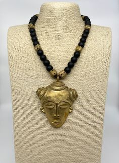 Go bold with this stunning African mask necklace for any occasion. Mask made from recycled brass items using the ancient lost wax method. Paired with onyx gemstones for durability and comfort. Necklace is approximately 27 inches long. Artisan Black Brass Necklaces, Black Brass Artisan Necklace, Artisan Black Brass Necklace, Artisan Gold Necklace With Black Beads, Artisan Black Brass Jewelry, Spiritual Gold Necklace With Black Beads, Black Brass Amulet Jewelry, Artisan Gold Jewelry With Black Beads, Traditional Adjustable Onyx Jewelry