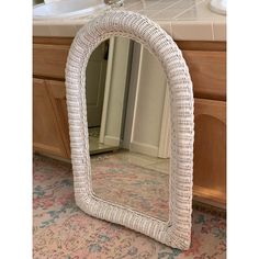 a white wicker mirror sitting on top of a bathroom counter