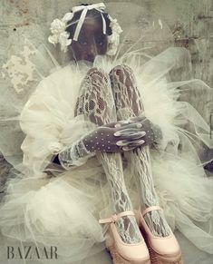 a mannequin dressed in white and wearing pink ballet shoes, with her hands on her knees