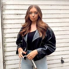 a woman is standing in front of a garage door with her hand on her hip