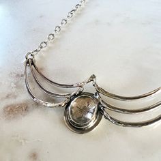 A gorgeous faceted clear topaz set in a handmade bezel, nestled between solid sterling silver castings of squirrel ribs. Beneath the sparkling topaz is a stamping of a single snowflake. The chain is delicate, but sturdy and measures 20" with a lobster clasp closure.Center piece of necklace measures about 2.75" wideTopaz measures 11mm x 13mm Nickel Free Sterling Silver Oval Pendant, Nickel-free Sterling Silver Jewelry With Oval Pendant, Nickel-free Sterling Silver Oval Pendant Jewelry, Antique Silver Hand Forged Sterling Silver Necklaces, Antique Silver Sterling Silver Jewelry With Oxidized Finish, Hand Forged Sterling Silver Necklace In Antique Silver, Silver Oval Pendant With Polished Finish, Silver Jewelry With Polished Oval Pendant, Silver Oval Pendant Jewelry With Polished Finish