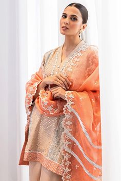 Wear this georgette kaamdani kurta in a honey beige shade with colour block details to your festive events. The zardoz and ribbon work around sleeves and neckline elevate the look. Pair it with tonal raw silk worked izaars and a peach organza dupatta with eyelet detailed scallop edging. Elegant Peach Lehenga With Dupatta, Elegant Peach Georgette Lehenga, Elegant Tissue Silk Dress With Gota Work, Elegant Peach Lehenga For Eid, Elegant Peach Designer Wear Lehenga, Elegant Designer Peach Lehenga, Orange Organza Sets With Resham Embroidery, Designer Tissue Silk Kurta With Dabka, Peach Dress With Zari Work In Traditional Drape