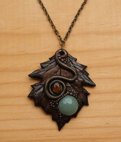 a necklace with an animal head and a stone in the center on a wooden surface