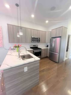 an empty kitchen with stainless steel appliances and wood flooring is pictured in this image