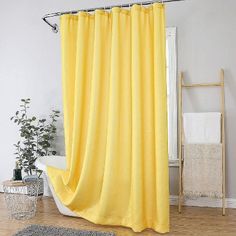 a yellow shower curtain in a bathroom next to a white bathtub and wooden floor