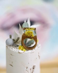 a wedding ring made out of wood and flowers on top of a small white cake