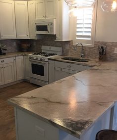 a kitchen with marble counter tops and white cabinets