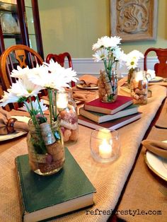 a table topped with books and vases filled with white flowers on top of it