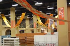 the interior of a large store with lots of shelves and banners hanging from the ceiling