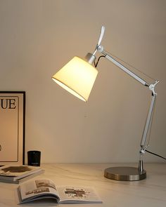 a desk lamp sitting on top of a table next to an open book