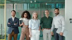 a group of people standing next to each other in front of a glass walled wall