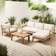 a couch and table on a deck with potted plants