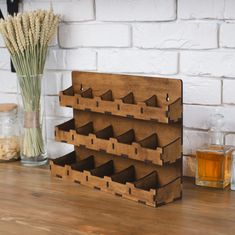 a wooden rack with six compartments on top of a table next to a glass vase