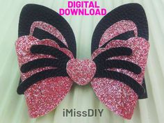 a pink and black bow with glitter hearts on it's side, sitting on top of a white sheet