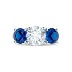 three stone engagement ring with blue sapphire stones on the sides and an oval diamond in the center