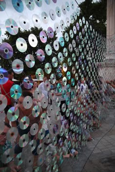 several people are standing in front of a wall with cds on it