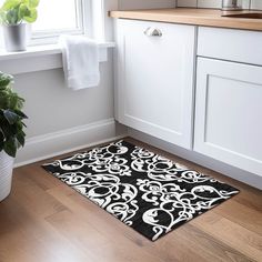 a black and white area rug on the floor next to a potted green plant