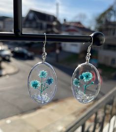 two dandelions in glass hanging from a window sill