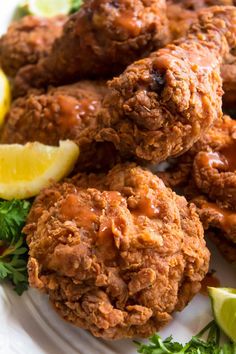 some fried food on a white plate with lemon wedges and ketchup sauce