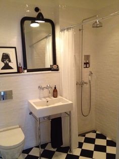 a bathroom with black and white checkered flooring, a toilet, sink, shower stall and mirror