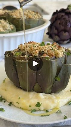 an artichoke is being drizzled over mashed potatoes on a plate