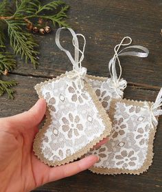 hand holding two tags with lace on them