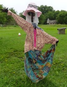 a woman in a dress and hat with her arms out, standing on the grass