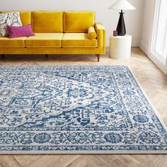 a living room with a yellow couch and blue rug