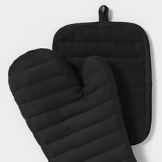 two black oven mitts sitting next to each other on top of a white table