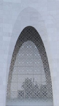 an arched window in the side of a white building with intricate metal work on it