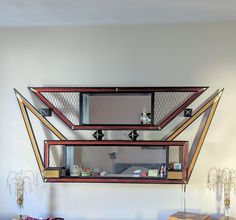 a mirror is hanging on the wall above a table with two vases and a box