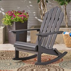 a wooden rocking chair sitting on top of a rug next to a potted plant