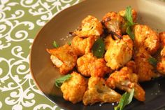 a plate full of cooked cauliflower on a green and white patterned tablecloth