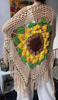 a woman is wearing a crocheted shawl with sunflowers on it