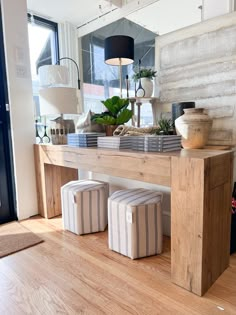 a wooden table with stools on it in front of a large mirror and potted plant