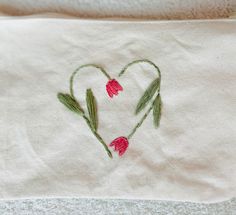 a heart - shaped piece of cloth with tulips embroidered on it