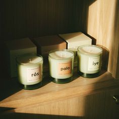 three candles sitting on top of a wooden shelf