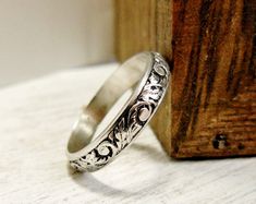 a silver ring sitting on top of a wooden block next to a piece of wood