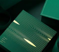 two green books sitting next to each other on top of a black table with gold trim