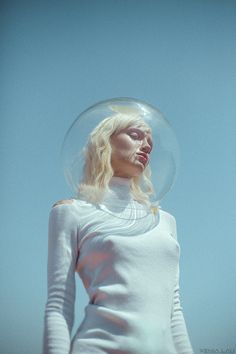 a woman with a bubble on her head is standing in front of the blue sky