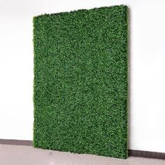 a wall covered in green grass on top of a white floor