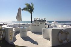 an outdoor bar on the beach with chairs and umbrellas in front of the ocean