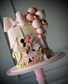 a pink and gold birthday cake with minnie mouse decorations