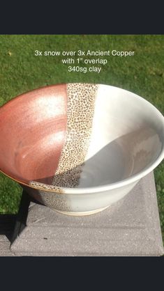 a white and brown bowl sitting on top of a cement block in the grass next to a green lawn