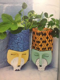 two planters with plants in them sitting on a shelf next to each other,