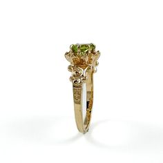 a yellow gold engagement ring with an oval cut green diamond in the center and two smaller round diamonds on each side