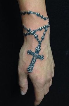 a person's hand with a rosary and cross tattoo on the middle of it