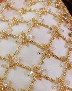 a piece of cloth with gold thread and beads on it's edge, sitting on a table