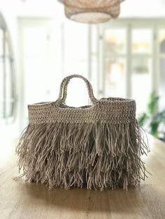 a handbag sitting on top of a wooden table next to a light hanging from the ceiling