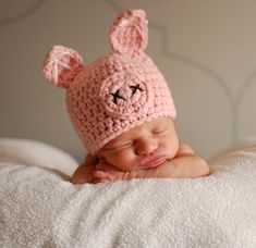 a baby wearing a pink crocheted bunny hat